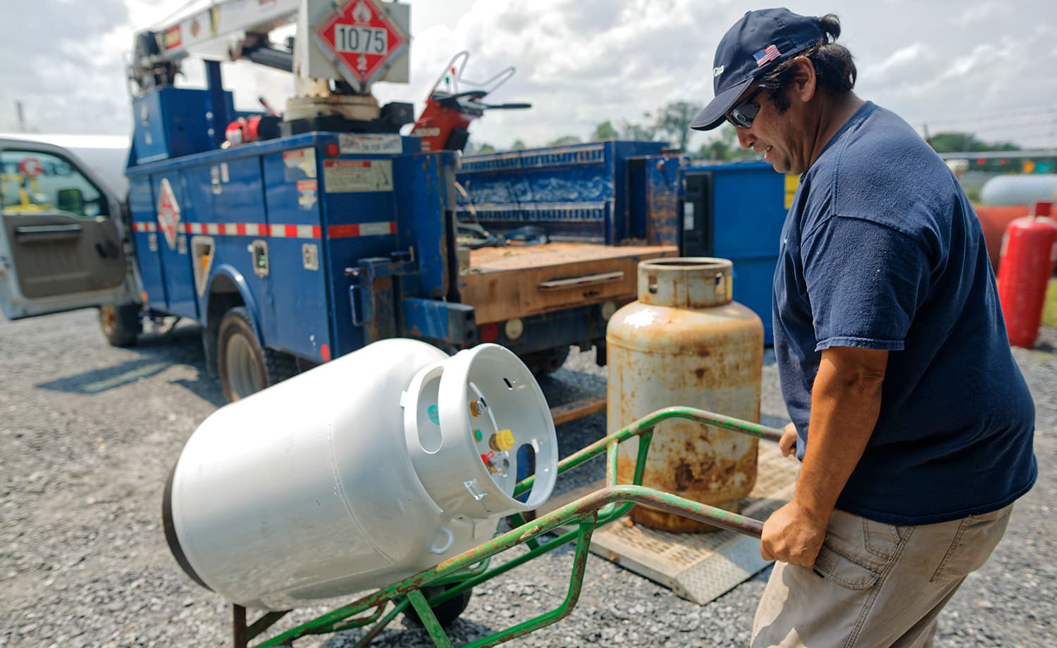 Man moving propane tank with a hand truck.