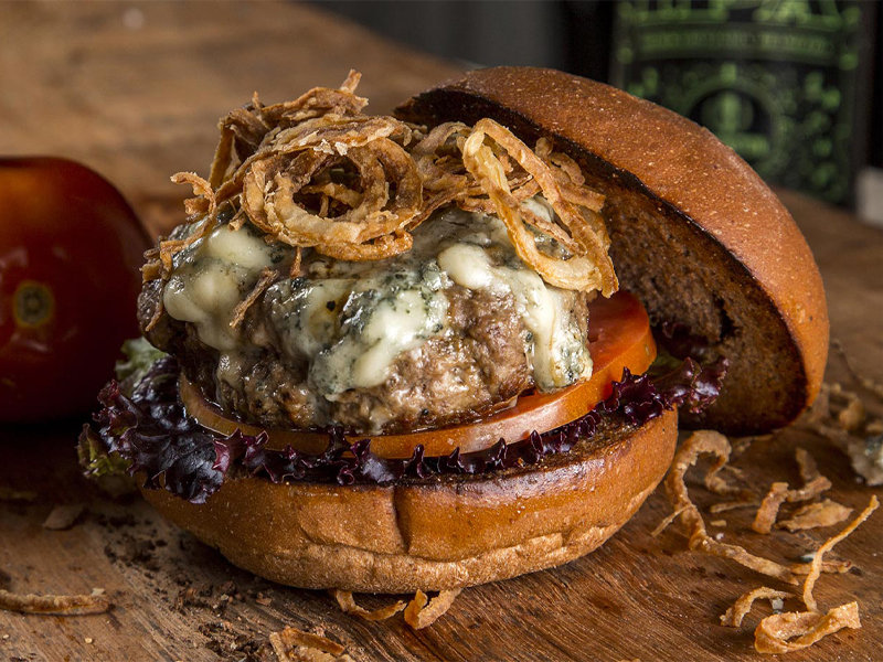 blue cheese burger on a bun with onion rings on top