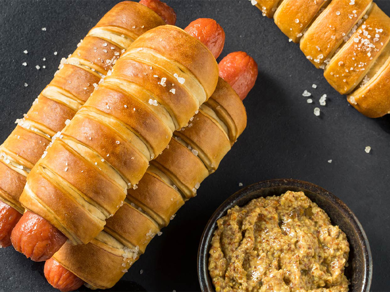 Pretzel wrapped hotdogs with mustard on the side