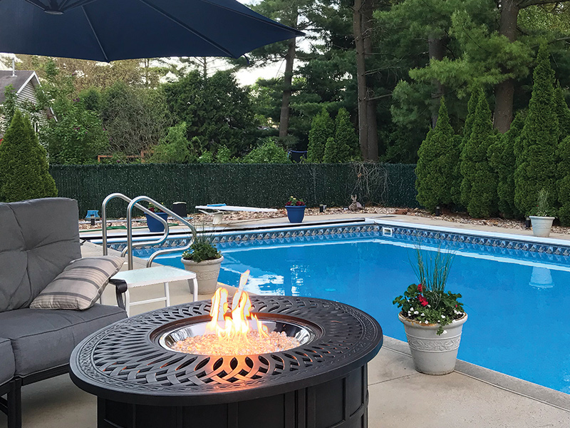 propane fire pit with hidden propane tank in back yard next to swimming pool