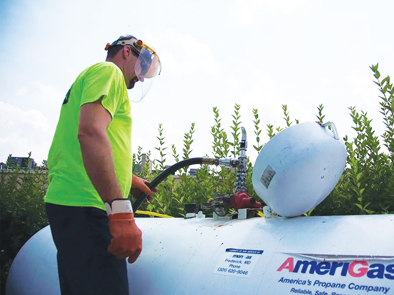 AmeriGas employee filling above ground propane tank with tank parts visible