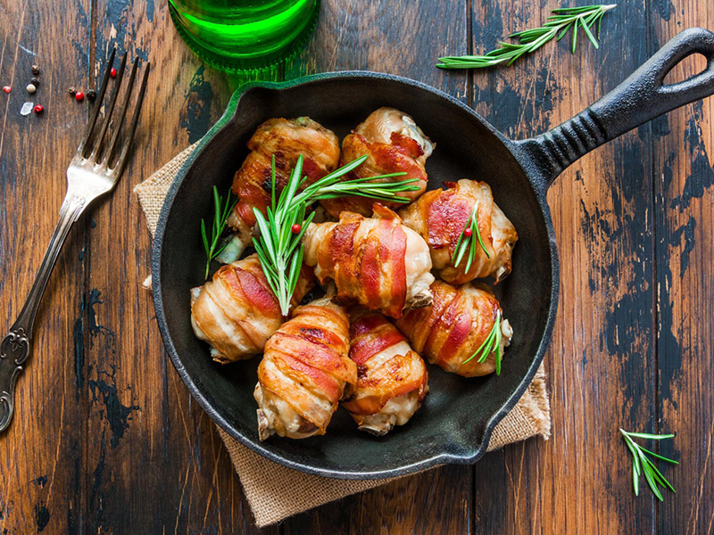 Grilled bacon wrapped chicken drumsticks in cast iron skillet