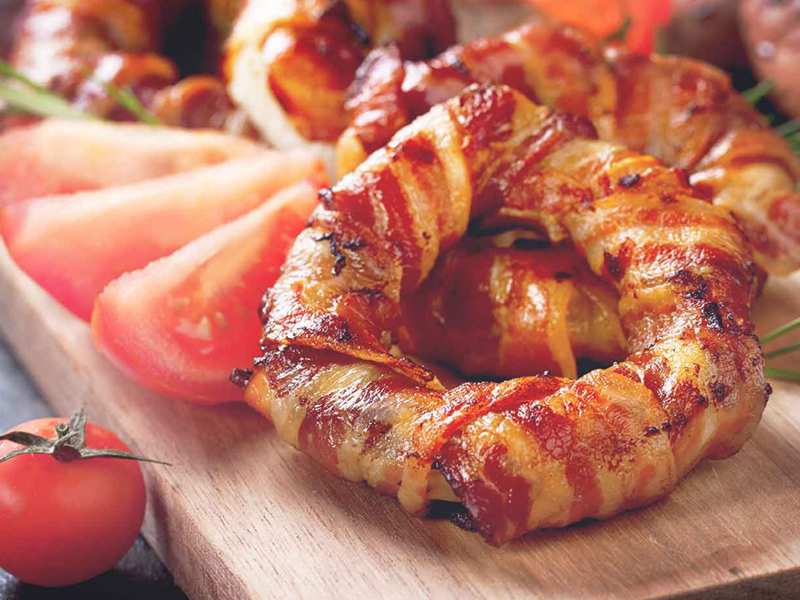 Grilled bacon wrapped onion rings on wood board