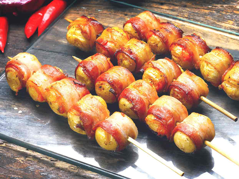 Grilled bacon wrapped potatoes on glass tray
