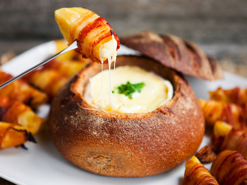 Cheese filled bread bowl being dipped into