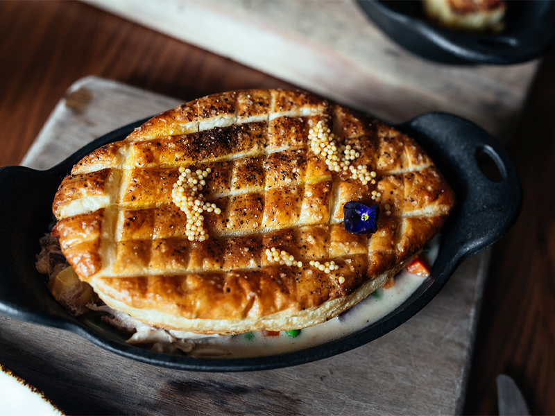 Skillet with chicken pot pie in it and a pastry top