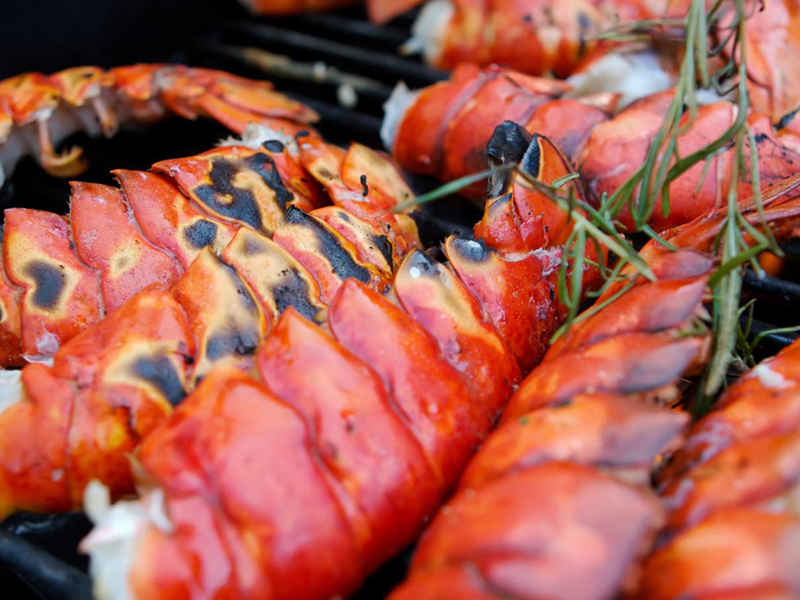 Grilled lobster tails stacked on tray