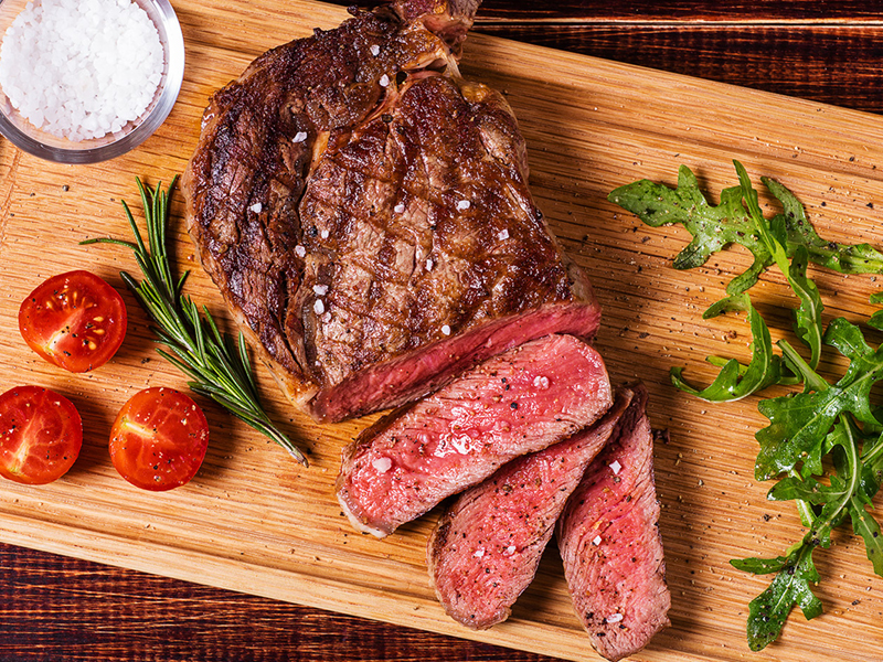 Grilled ribeye steak with tomatoes and arugula