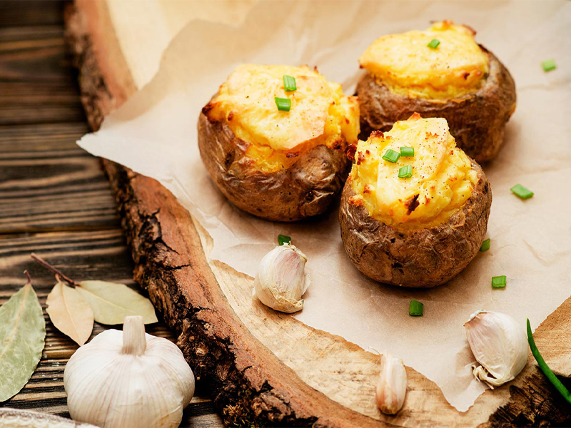 Potatoes and garlic cloves on paper on a slice of wood