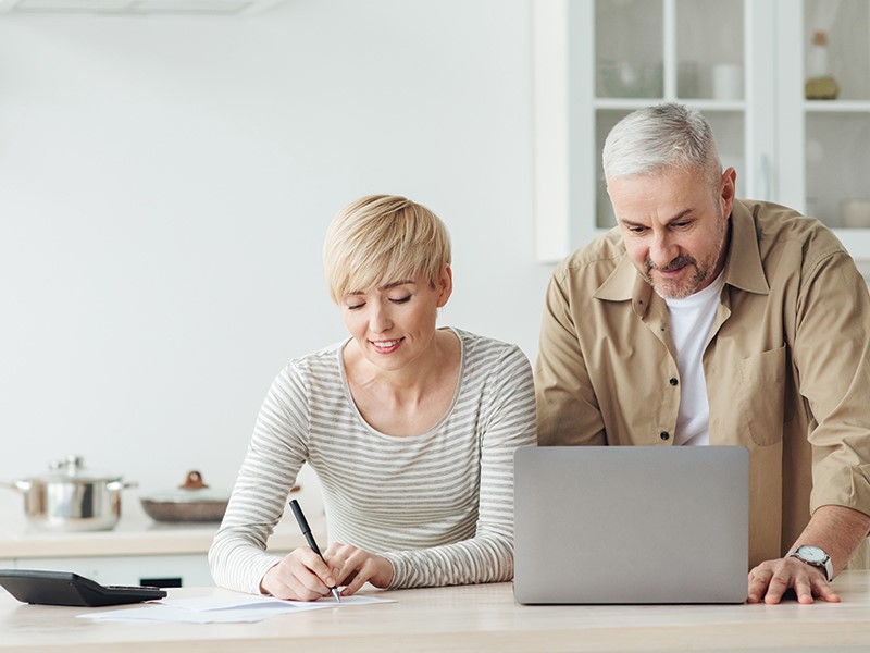 older couple with silver hair looking at laptop for propane pricing and taking notes