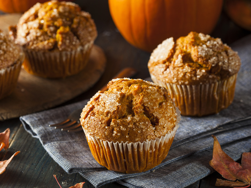 pumpkin muffins in front of a pumpkin on a table