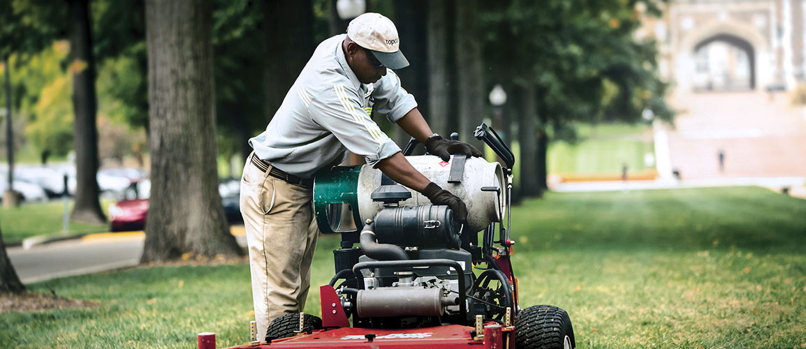 Landscaper inspecting lawn mower.