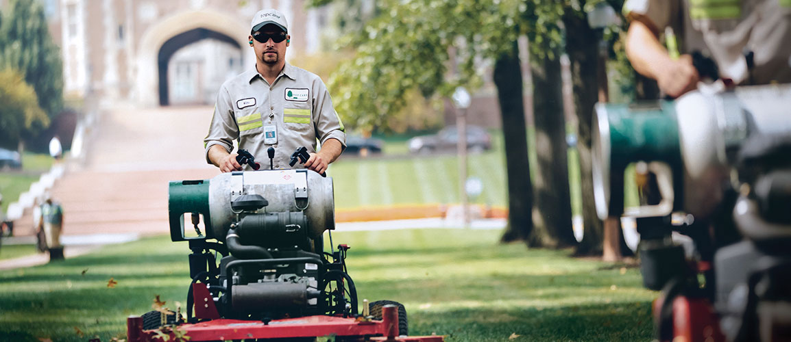 Landscaper driving lawn mower.