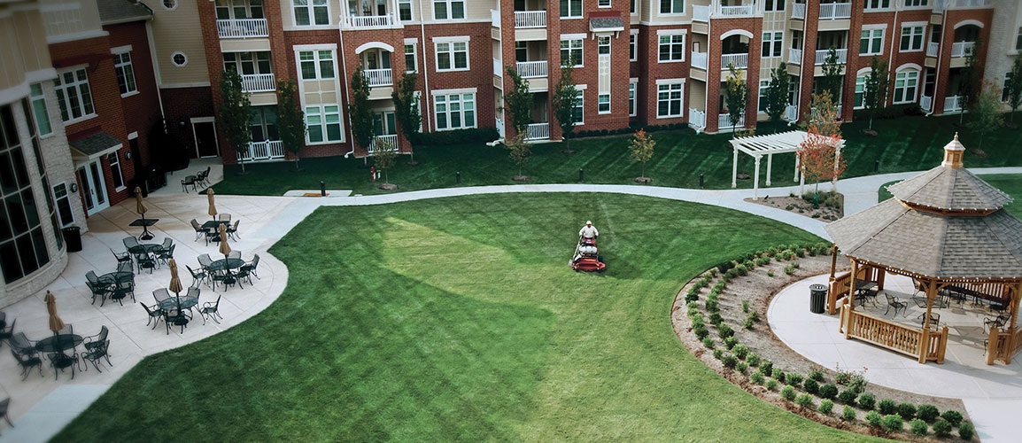 Grass being mowed in the courtyard of a large complex.