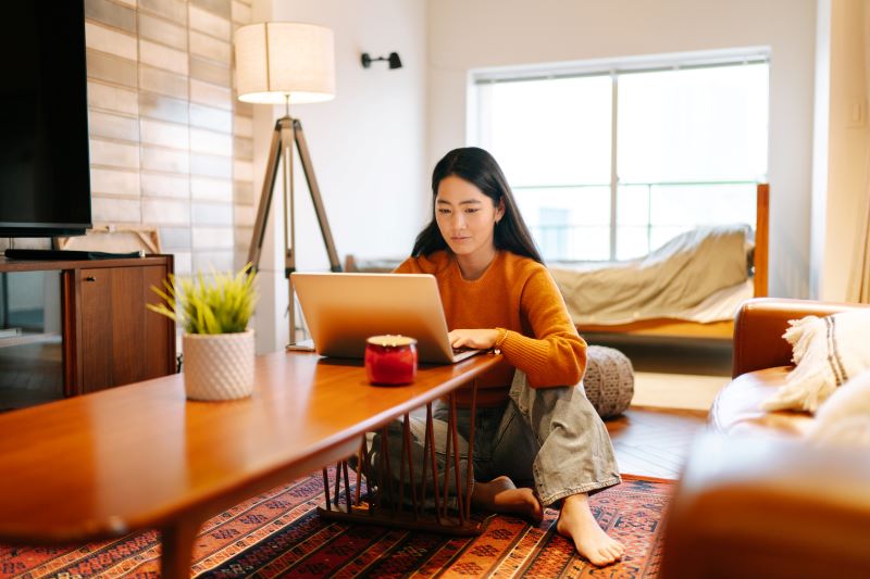 Woman sitting on the floor at a table looking at a laptop