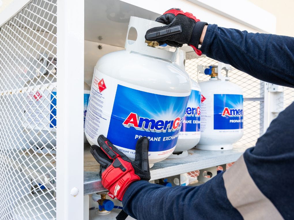 AmeriGas delivery driver loading a propane tank cage with new tanks