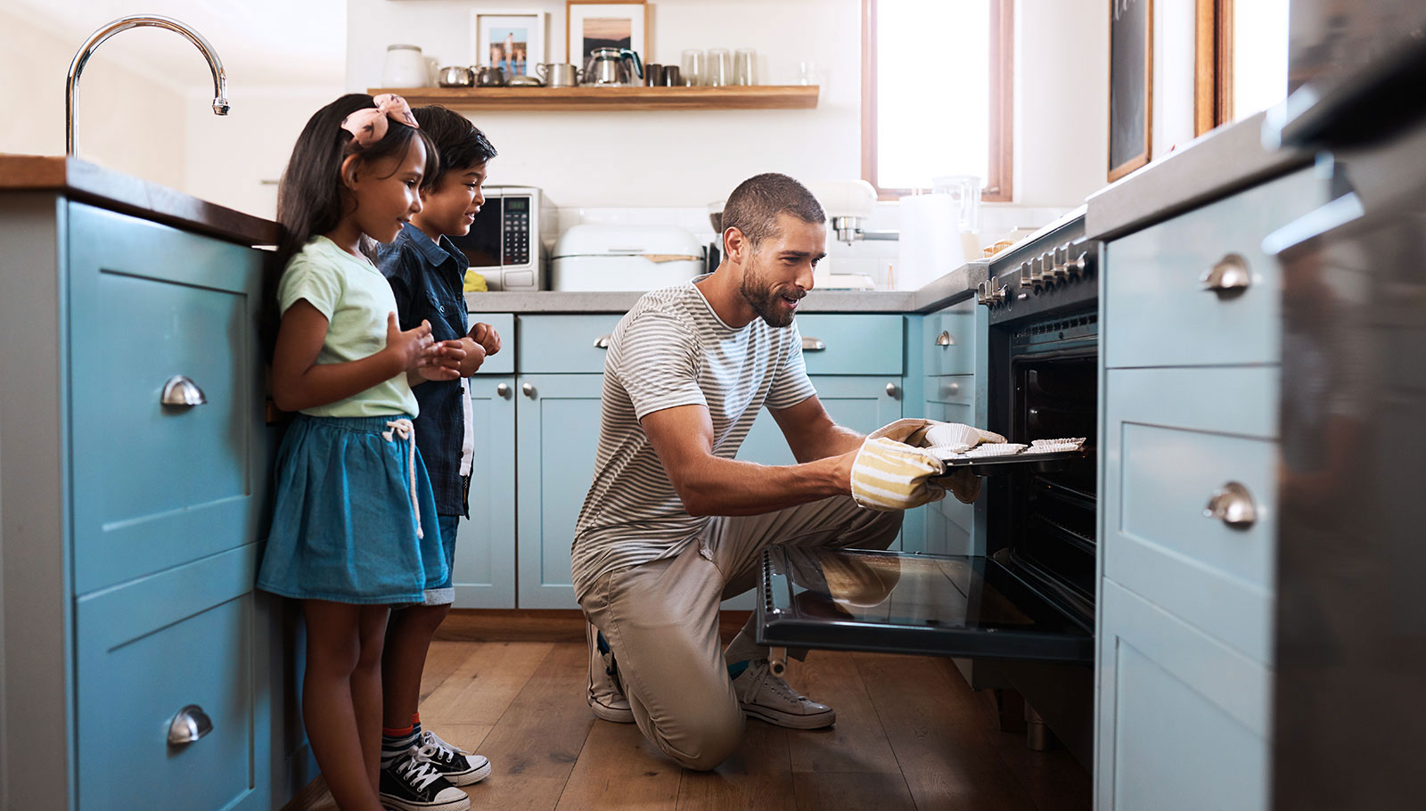 A man using a propane oven to bake with his children