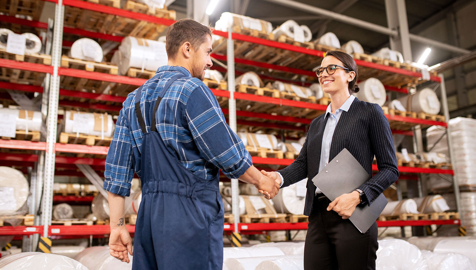 Business partners shaking hands in a warehouse.