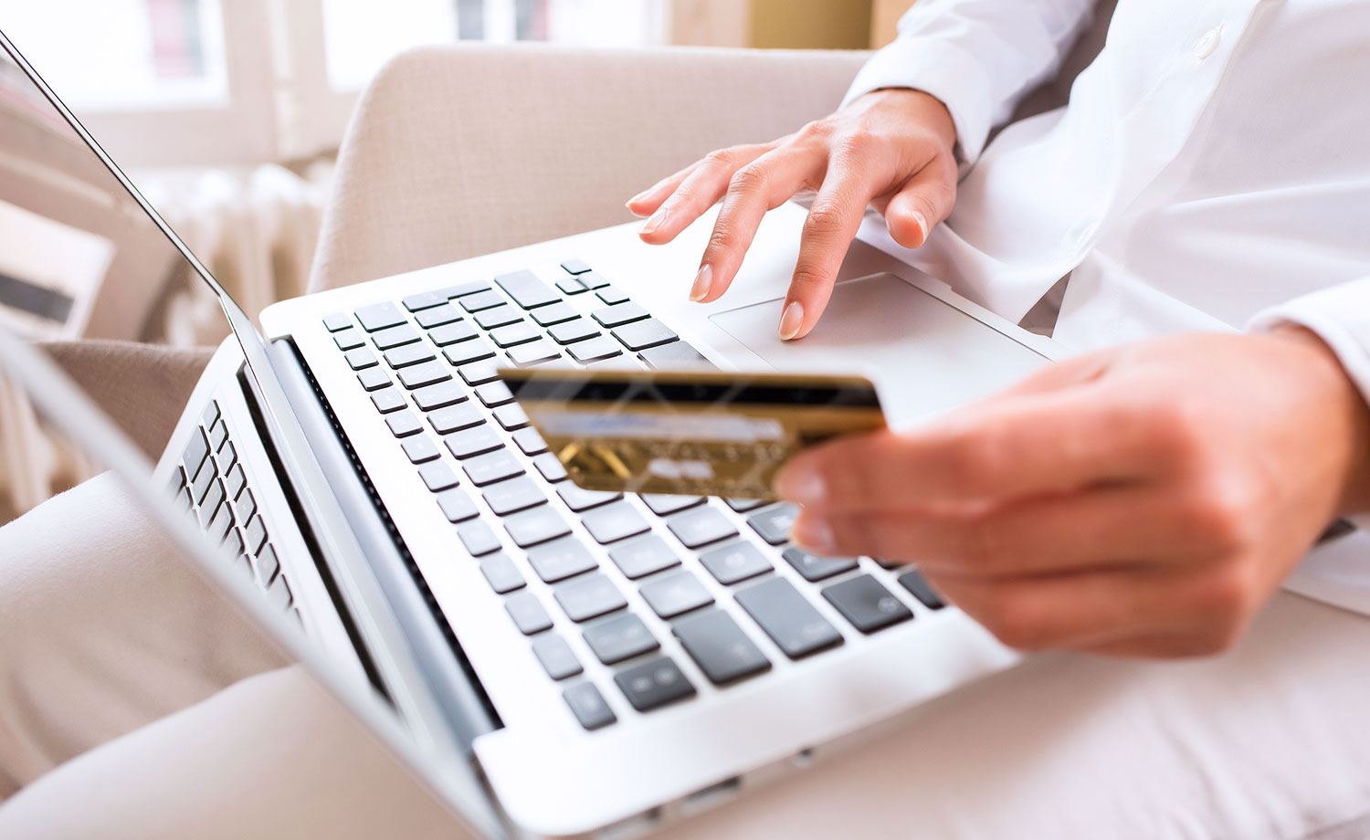 Person holding credit card in front of a laptop.