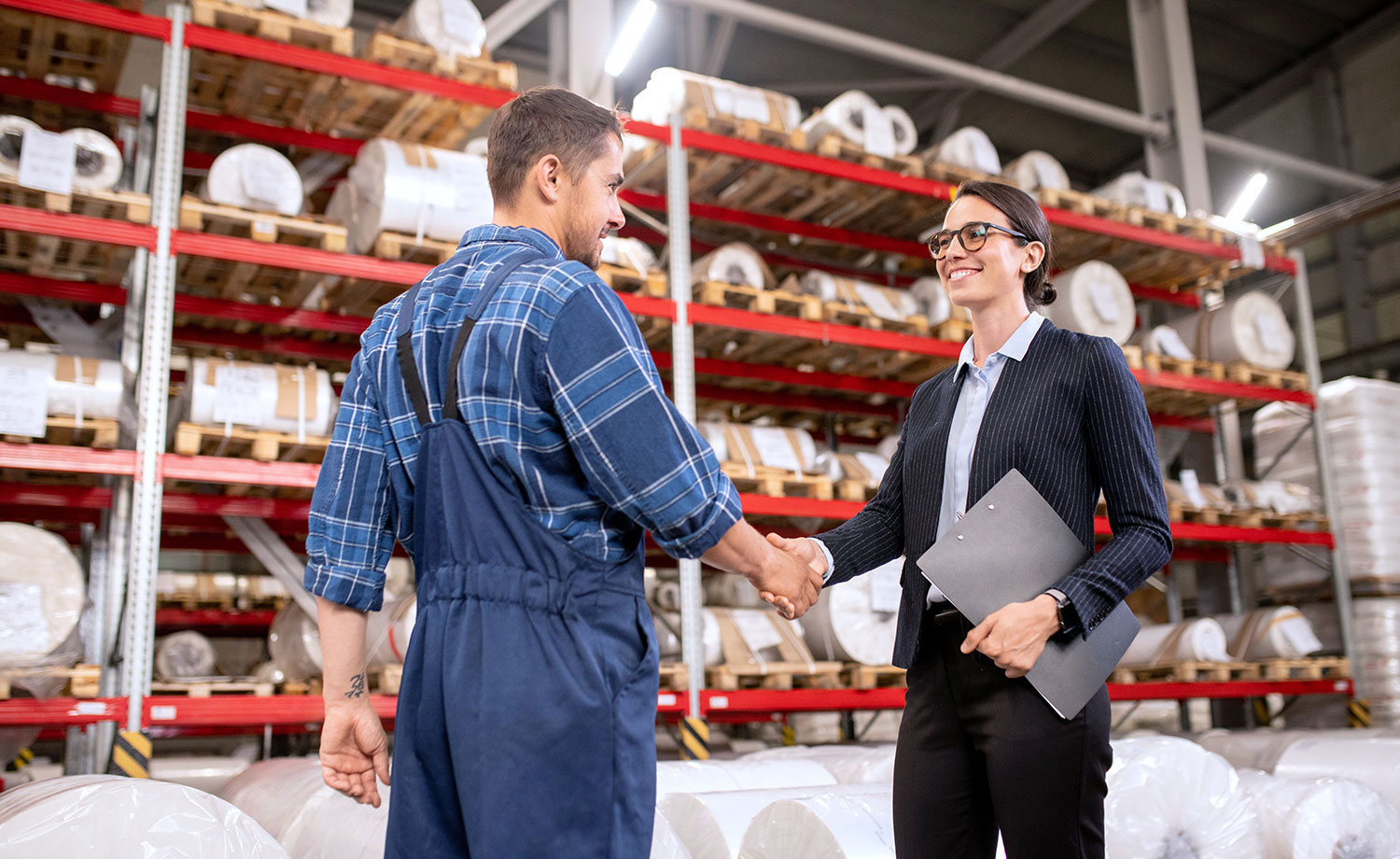 Business partners shaking hands in a warehouse.