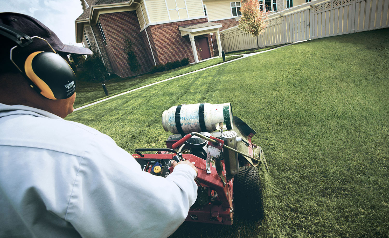 Man with propane powered lawn mower.