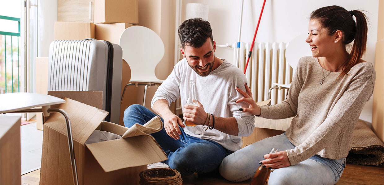 People sitting in room surrounded by moving boxes.
