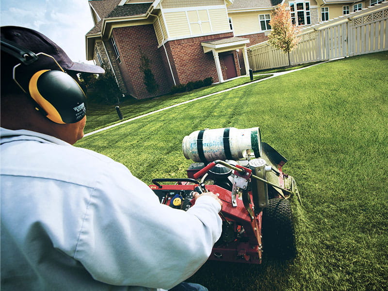Man with propane powered lawn mower.