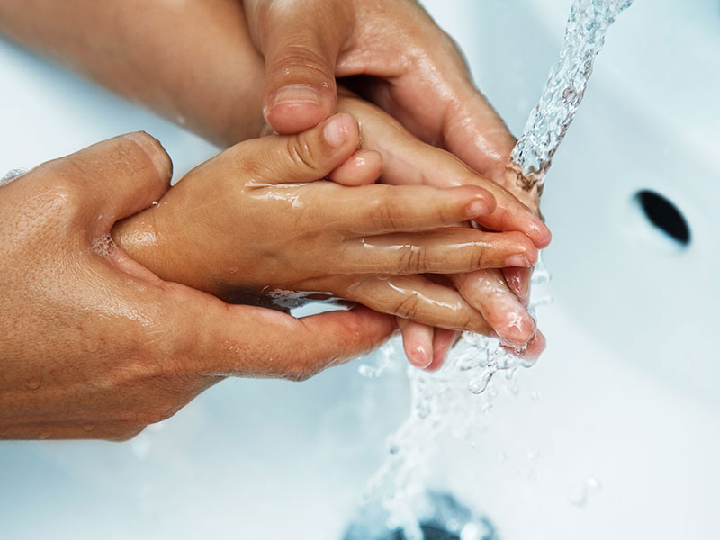 Parent helping child wash their hands.