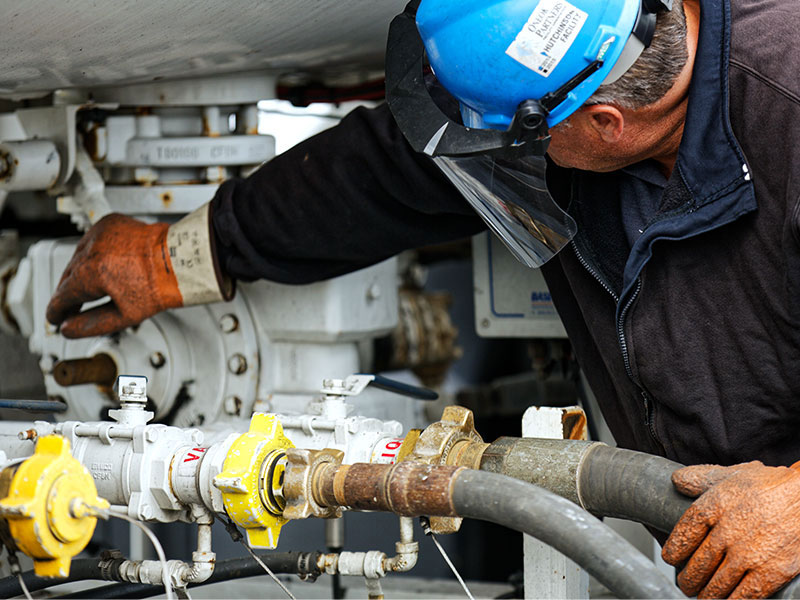 Man in safety gear inspecting propane tank.