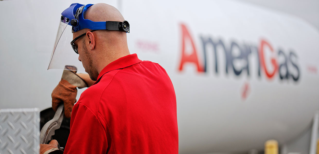 Man in safety gear working on propane tank.